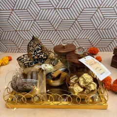 This Diwali hamper is curated with care on a golden tray, featuring jars of treats, Ferrero Rocher chocolates, and a beautiful hamsa-shaped T-light holder. It's a perfect blend of indulgence and festive blessings.