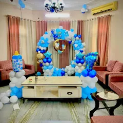 A full living room setup for a baby boy's celebration. The circular balloon arch in shades of blue and white creates a perfect centerpiece without taking up too much space.