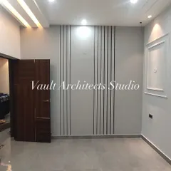 A glimpse of a finished bedroom or living space, showcasing simple elegance. The wall features a combination of vertical grooves and classic molding, adding texture and character to the room.
