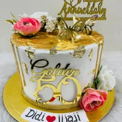 A golden 50th anniversary cake for a special "Didi & Jijaji." This white and gold masterpiece is decorated with flowers, butterflies, and a "Golden 50" topper.