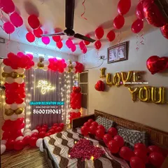 A wider view of the romantic room setup, showing how the ceiling balloons, balloon arch, and bed decorations work together to fill the space with love and celebration.