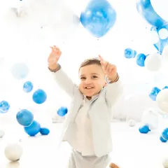With arms raised in excitement, a one-year-old boy plays amidst a sea of balloons. This candid shot is full of energy and joy, showcasing the fun and interactive nature of my milestone sessions.