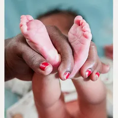 The tiny feet of a newborn, held gently during a naming ceremony. We believe in capturing the delicate details that tell the story of a new beginning.