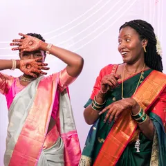 Fun and playful moments at a cross-cultural wedding. These two women in beautiful sarees share a laugh, showcasing the joy of blended celebrations.
