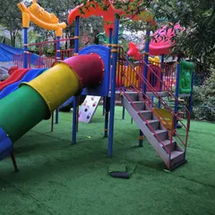 The colorful play structure looks even better against the vibrant green of the new artificial grass floor at the Nainital Eco Cave Garden.
