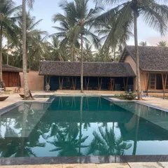 The recently completed farmhouse in Hassan, Karnataka, set within a coconut grove. The design features a large swimming pool as its centerpiece, with living spaces that open directly onto the deck.