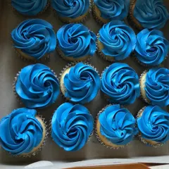 A box of classic blue frosted cupcakes, perfect for a "it's a boy" baby shower or a blue-themed birthday party. The simple rosette piping is elegant and timeless.
