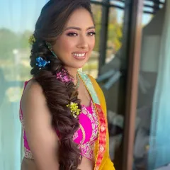 Popping colors for a Mehendi look! This side-swept fishtail braid is adorned with vibrant flowers, adding a playful and colorful touch that’s perfect for the celebration.