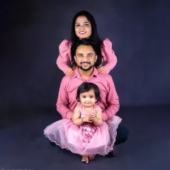 A classic family portrait with a fine-art touch. The coordinated outfits and creative pose against a dark backdrop create a stunning, artistic image that feels both timeless and modern.