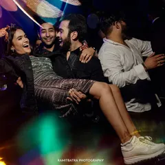 A fun moment from the after-party where the bride is lifted by her friends on the dance floor, laughing joyfully.