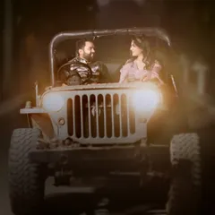 A close-up shot of a couple in our vintage jeep at night. The warm glow of the headlights creates an intimate and cinematic feel.
