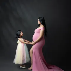 A touching moment between a mother and her daughter as they wait for the new baby. This portrait highlights the special bond they share, with the daughter gently holding her mother's hand on the baby bump.