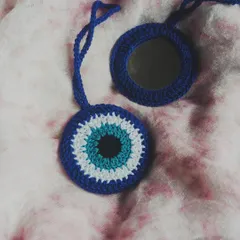 Our crochet evil eye bag charm, which cleverly doubles as a pocket mirror. This unique accessory is designed to protect you from 'buri nazar' while being a practical addition to your handbag.