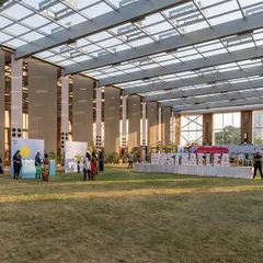 This wide shot shows the scale of the glass pavilion and how it can host large community gatherings. The transparent structure allows the event to feel like it's part of the surrounding landscape, creating a truly unique experience.