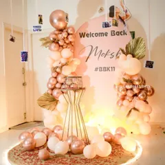 The complete welcome back setup, featuring rose gold balloons and a personalized photo display.