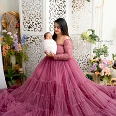 A quiet moment between a mother and her newborn. Dressed in a stunning gown, she cradles her baby, creating a portrait of maternal love and serenity.
