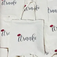 A closer look at the elegant 'itraake' tote bag. The combination of a delicate script and a small floral detail creates a sophisticated look on this natural cotton bag, perfect for fashion and lifestyle brands.