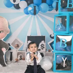 This Boss Baby theme features transparent boxes spelling 'BABY' filled with balloons, and a backdrop with money-themed props, creating a playful and stylish set for a first birthday shoot.