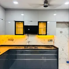 This is a modern modular kitchen I designed, featuring a sleek two-tone look with glossy grey and white cabinets. I used under-cabinet LED lighting to illuminate the marble-patterned backsplash and black granite countertop, creating a workspace that is both stylish and practical.