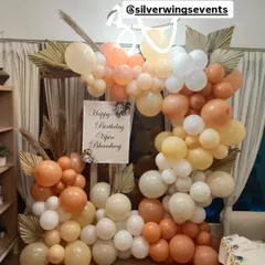 A modern and chic birthday setup with a boho touch. This organic balloon arch in neutral tones is accented with dried palm leaves and a custom neon sign.