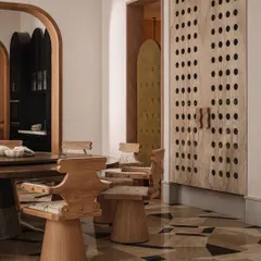 Another angle of the dining room, looking towards a secondary entrance. The perforated wooden screen and bold flooring create a space that is rich in pattern and texture.