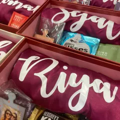 A closer look inside our personalized bridesmaid gift box. Each box contains a custom 'Riya' robe, a personal photo frame, and a selection of chocolates and treats to make her feel truly special.
