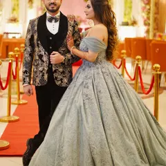 This couple looks picture-perfect on their special day. The bride rented this elegant grey-blue ball gown, which complements the groom's formal attire beautifully against the red carpet entrance.