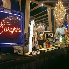 A stylish Sangria station with a neon sign, set up as part of a larger bar for a wedding reception.