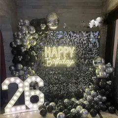 This is another example of a glamorous shimmer wall backdrop, here in a black and silver theme for a 26th milestone. The combination of chrome balloons, a neon sign, and marquee numbers creates a high-energy party atmosphere.