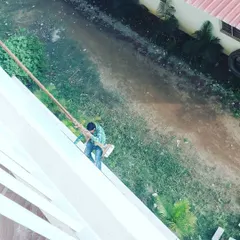 A high-angle view of a painter using a safety harness to work on the facade of a tall building. I am fully equipped for high-rise exterior painting jobs in Bangalore.