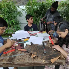 A facilitator guides participants through the basics of leather craftsmanship. In this workshop, attendees learn techniques to create their own wallets and journal covers using a simple set of tools.