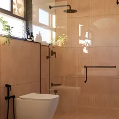 The client's brief was simple: "I want mud in my bathroom." We delivered this cozy, earthy design using warm-toned tiles and black matte fixtures to create a rustic yet modern retreat.