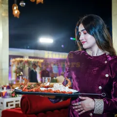 A member of our serving staff in an elegant velvet uniform, holding a tray of appetizers. We ensure our team's appearance matches the high standard of your event.