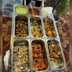 A close-up of our live grill cart, loaded with a variety of freshly grilled kebabs and tikkas, including paneer, chicken, and soya chaap, served with chutneys.