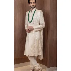 A closer look at the fine craftsmanship of our ivory sherwani, paired with an emerald green mala. This combination of classic ivory and rich color adds a touch of personal style to traditional groomswear.