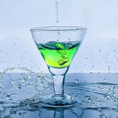 A vibrant green drink being poured into a glass, with surrounding splashes creating a refreshing and energetic scene.