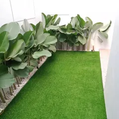 A clean and simple landscape design for a narrow space. We used artificial turf for the ground cover and lined the wall with large-leafed plants in a bed of white pebbles for a modern, minimalist look.