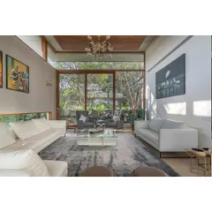 Floor-to-ceiling windows frame the lush garden like a living work of art, making the landscape an integral part of the interior design.