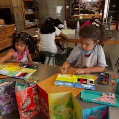 A young artist carefully illustrates a panel for her accordion-style book. These book-making projects combine drawing, painting, and storytelling into one unique creation.
