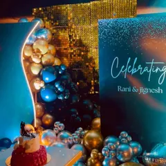 This view shows the celebration backdrop with the cake table in the foreground. The integrated neon lighting along the curve of the backdrop adds a sophisticated glow to the entire setup.