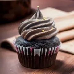 A close-up of my classic chocolate cupcake. It has a rich, moist chocolate base and is topped with a perfect swirl of velvety chocolate frosting and a few gold pearls for a touch of elegance.
