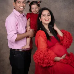 A beautiful family portrait filled with smiles. The matching red outfits for mom and daughter are an adorable touch.