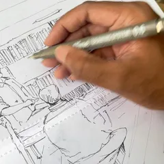 A close-up of my hand as I work on the pen sketch of the bookstall, adding details to the figures and shelves.