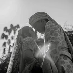 A powerful black and white silhouette of a couple against the bright sky. The high contrast and low angle create a dramatic and timeless portrait.
