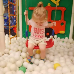 A "Big Sister" enjoys a gentle swing over the ball pit in our dedicated toddler area.