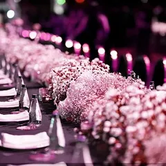 A close-up of the pink-lit tablescape, showing the beautiful floral runners and the unique, modern chairs.