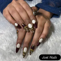 A fierce and fashionable design on long stiletto nails. This set combines deep burgundy, leopard print, and a bold white and gold accent for a high-fashion statement.