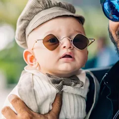 This little guy is already stealing hearts in his custom beige suit, complete with a tiny bowtie and cool shades. It's the perfect dapper look for a special occasion.