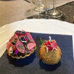 A duo of amuse-bouche: a vibrant beet tartlet and a rich confit duck croquette.