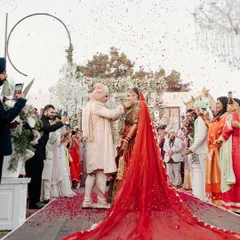 The bride, Rhea, during the Varmala ceremony, with a long, dramatic veil trailing behind her. A moment of tradition captured with a sense of modern scale.